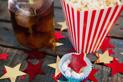 Popcorn, confectionery and drink with 4th july theme on wooden table