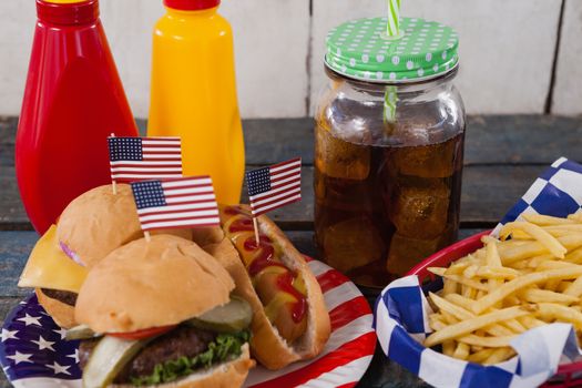 Close-up of snacks and cold drink on wooden table with 4th july theme