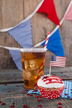 Decorated cupcake and cold drink with 4th july theme on wooden table