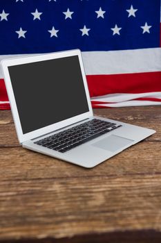 Laptop and American flag on wooden table with 4th july theme