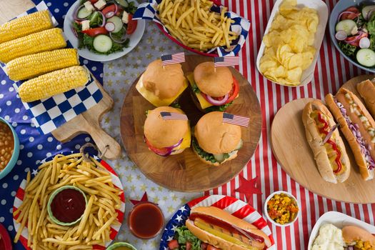 Close-up of hot dogs and burgers on wooden table with 4th july theme