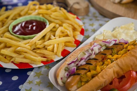 Close-up of hot dog and french fries on wooden table with 4th july theme