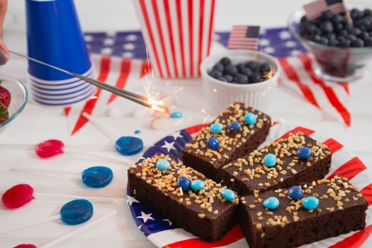 Close-up of sweet food and burning crackers decorated with 4th july theme on wooden table