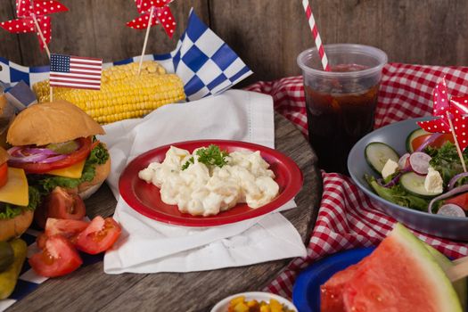 Snacks and cold drink decorated with 4th july theme on wooden table