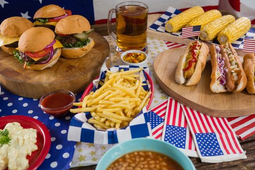 Close-up of hot dogs and burgers on wooden table with 4th july theme