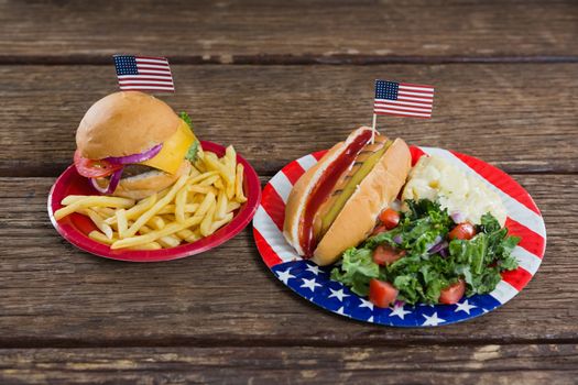 Close-up of burger and hot dog on wooden table with 4th july theme