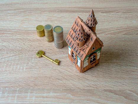 Model of a house, Stack of European Euro coins and golden key On Wooden Table. Real estate agency, mortgage loan, lottery, buying property.Home loan and investment concept. Copy space