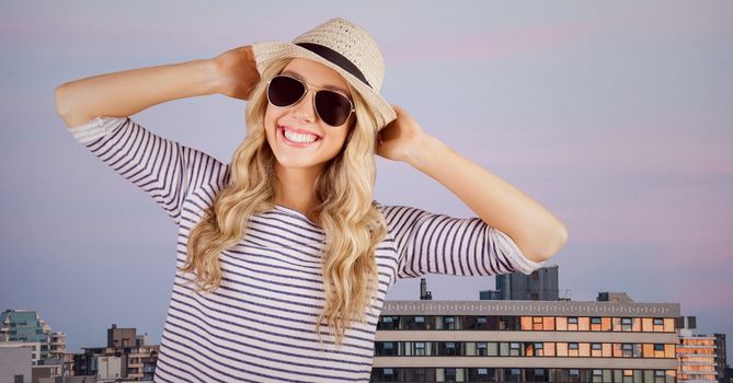 Digital composite of Woman in summer clothes with hands on head against buildings and evening sky