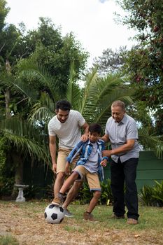 Full length of family playing soccer on field in yard