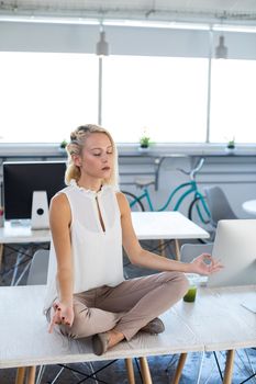 Female executives doing yoga on desk in office