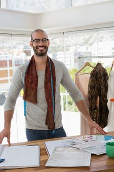 Portrait of fashion designer standing at table in office