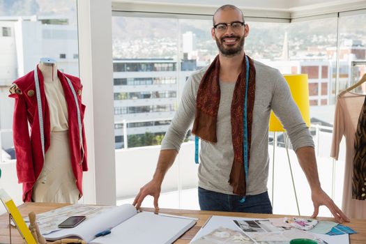 Portrait of fashion designer standing at table in studio