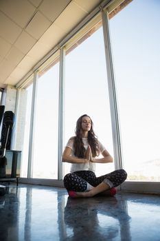 Businesswoman doing yoga by window on floor at office