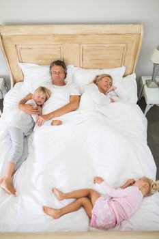 Family sleeping on bed in the bed room at home