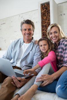 Portrait of happy family using laptop together in living room at home