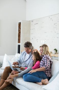 Family using laptop together in living room at home