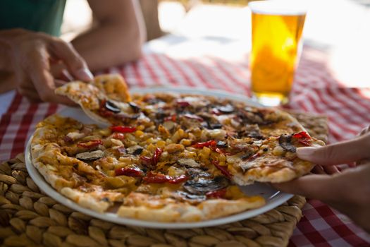 Cropped hands on friends having pizza at table outdoors