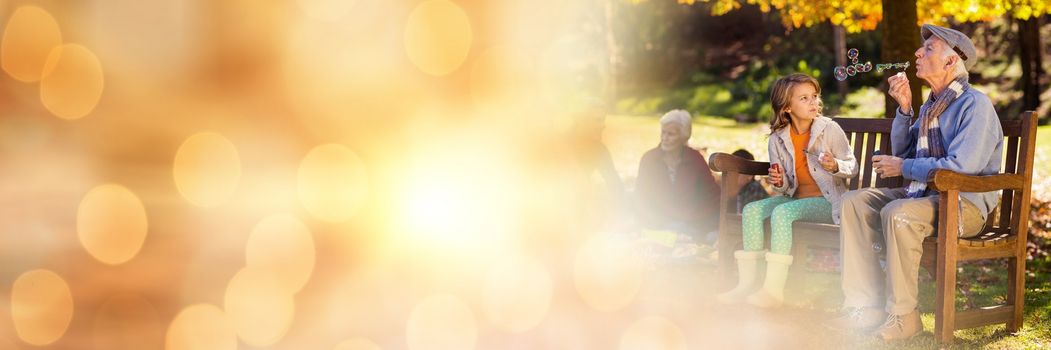 Digital composite of Family in park blowing bubbles with orange bokeh transition