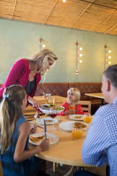 Mother serving food to family in restaurant