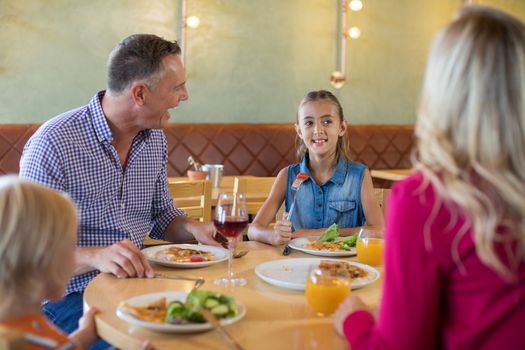 Happy family talking while having food at restaurant