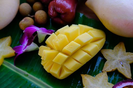 Delicious Fresh exotic fruits slices of carambola, mango, longan and pink apple on banana leaf. 