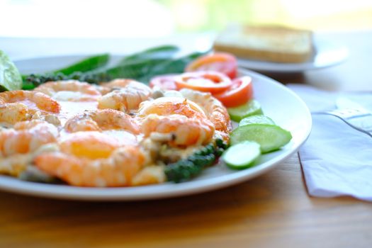 Delicious breakfast Fried eggs with prawns decorate fresh vegetables and toast, asian style food. Selective focus close up. 