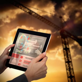 Cropped image of businesswoman holding digital tablet against 3d image of crane against cloudy sky