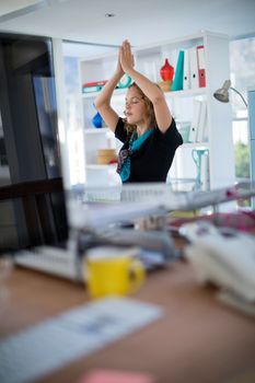 Female executive doing yoga on desk in office