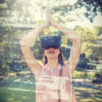 Woman standing with her hands joint while using a VR 3D headset in the park on a sunny day