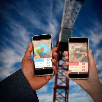 Cropped hands of man and woman holding mobile phones against 3d image of red crane
