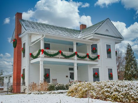 A traditional white two story house decorated for Christmas in fresh snow