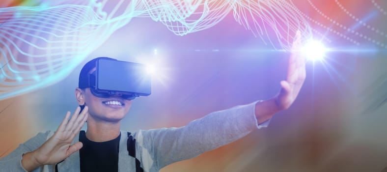 Smiling young woman gesturing while wearing virtual reality glasses against abstract glowing black background