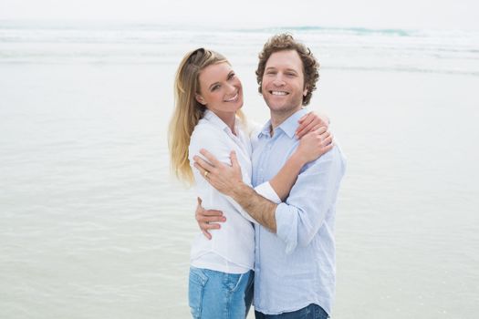 Portrait of a happy romantic young couple embracing at the beach