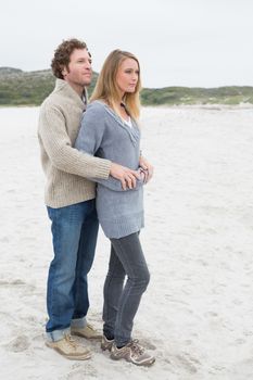 Full length of a relaxed romantic young couple standing together at the beach