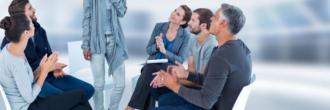 Digital composite of Group of People sitting in circle with ladt standing up and clapping hands