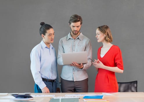 Digital composite of Business people at a desk looking at a tablet against grey background