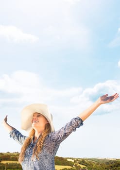 Digital composite of Millennial woman with arms out against hills and Summer sky