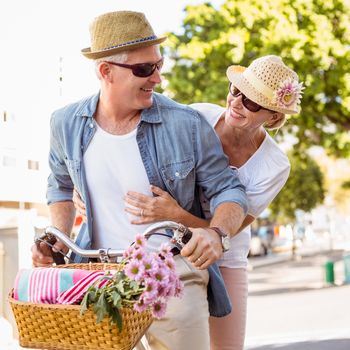 Happy mature couple going for a bike ride in the city on a sunny day