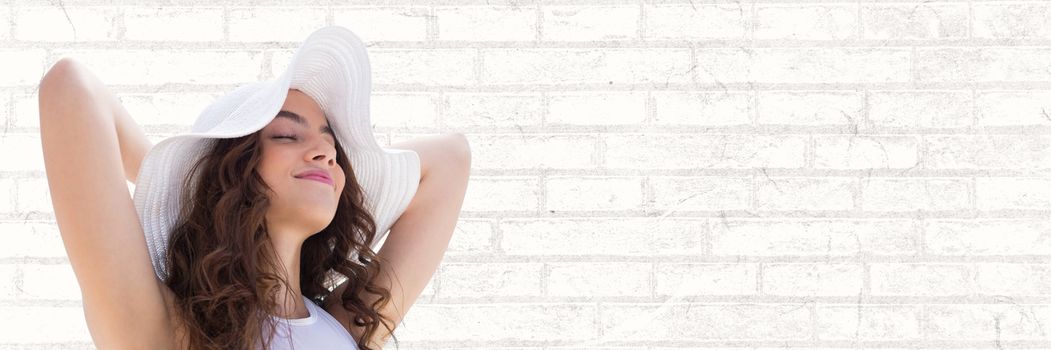 Digital composite of Portraiture of woman in summer hat relaxing against white brick wall