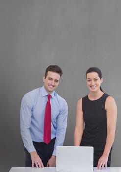 Digital composite of Happy business people at a desk using a computer against grey background