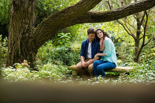 Romantic couple sitting on bench in garden on a sunny day