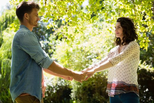 Romantic couple holding hands in garden on a sunny day