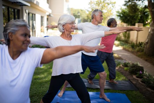 Multi-ethnic senior people stretching while exercising on yoga mats at park