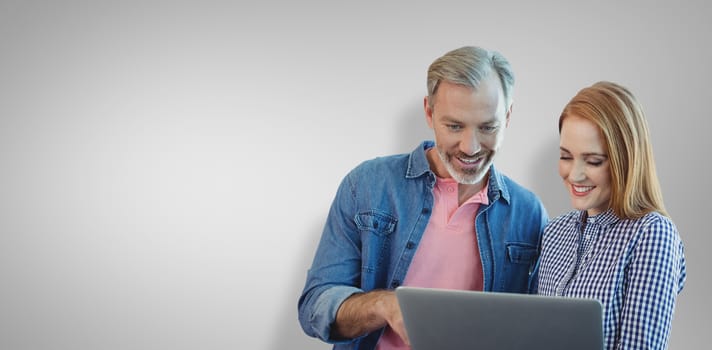 Portrait of smiling business people using laptop against grey vignette