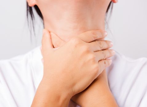 Asian beautiful woman Sore Throat or thyroid gland problem her useing Hand Touching Ill Neck on white background with copy space, Medical and Healthcare concept