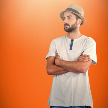 Thoughtful model standing with arms crossed against orange background 