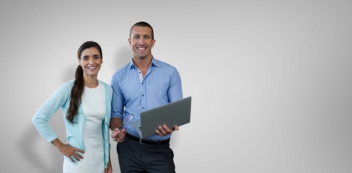 Smiling business people using a laptop against grey vignette