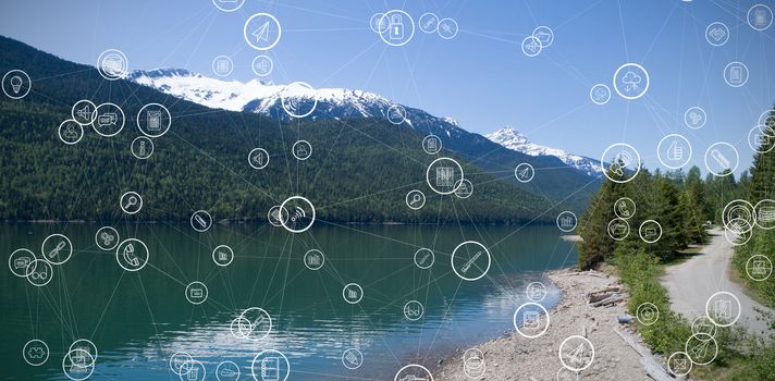 Technology icons against snowcapped mountain range by river with reflection against sky