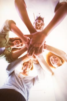 Directly below portrait of business people stacking hands while standing in office