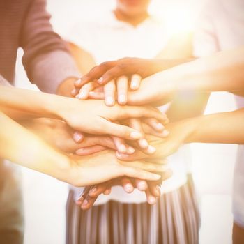 Close up of colleagues stacking hands while standing in office